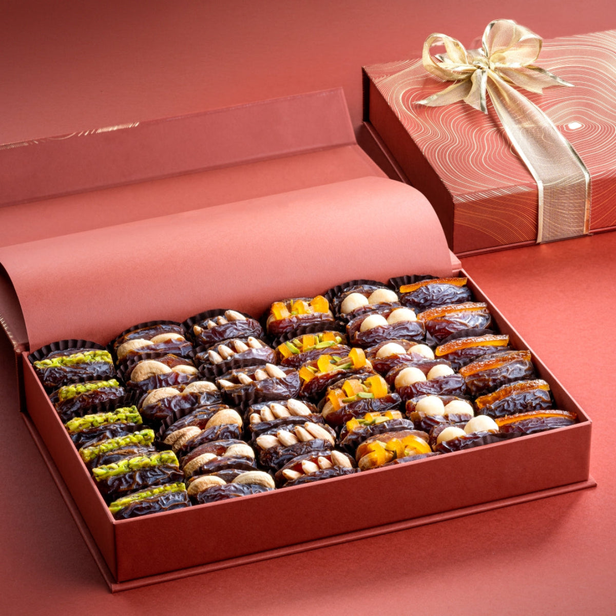 Open rust gift box with 36 assorted Mejdool dates stuffed with pistachios, almonds, cashews, macadamia nuts, mango peel, and candied orange peel.