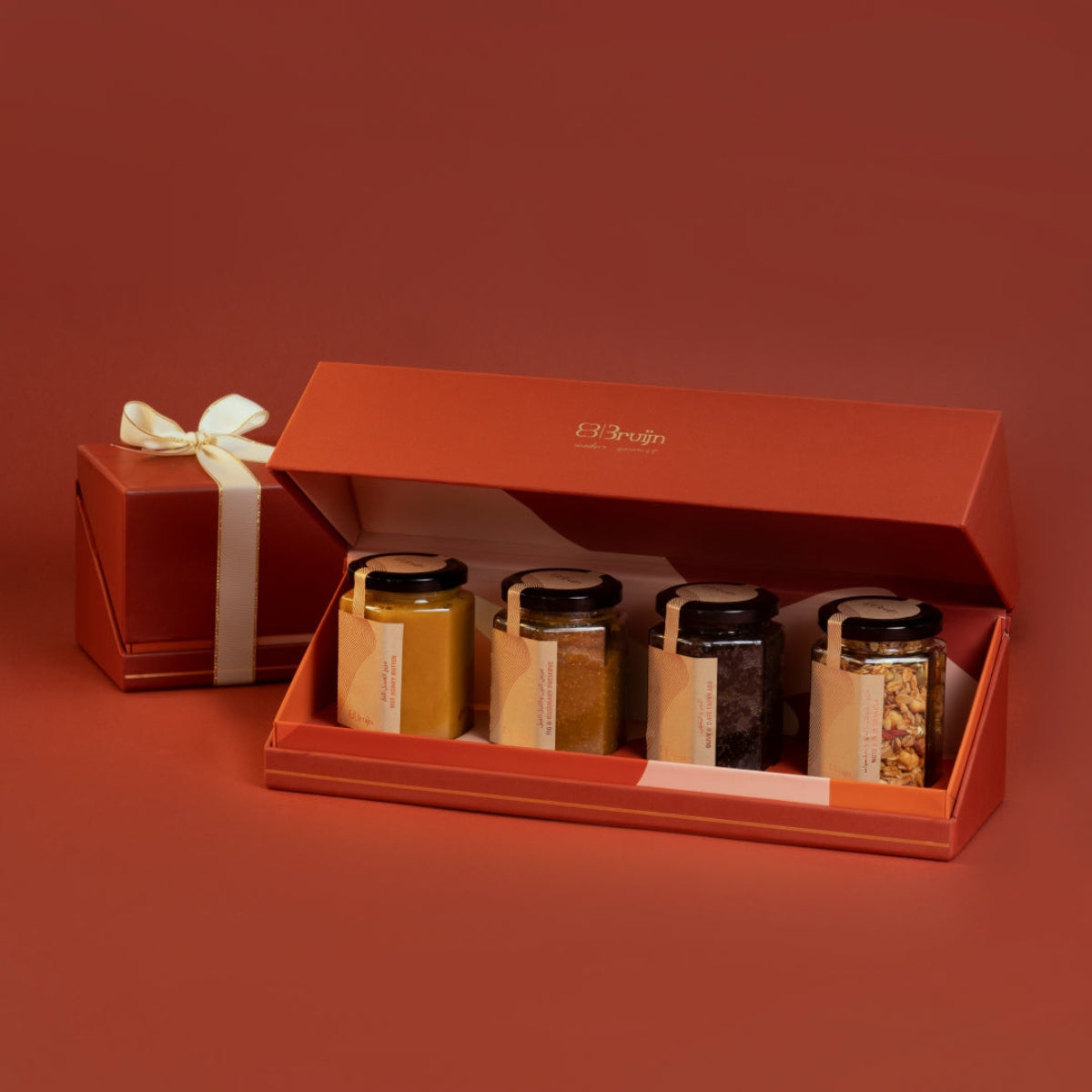 Open gift box with jars of honey and a smaller gift box on a red background