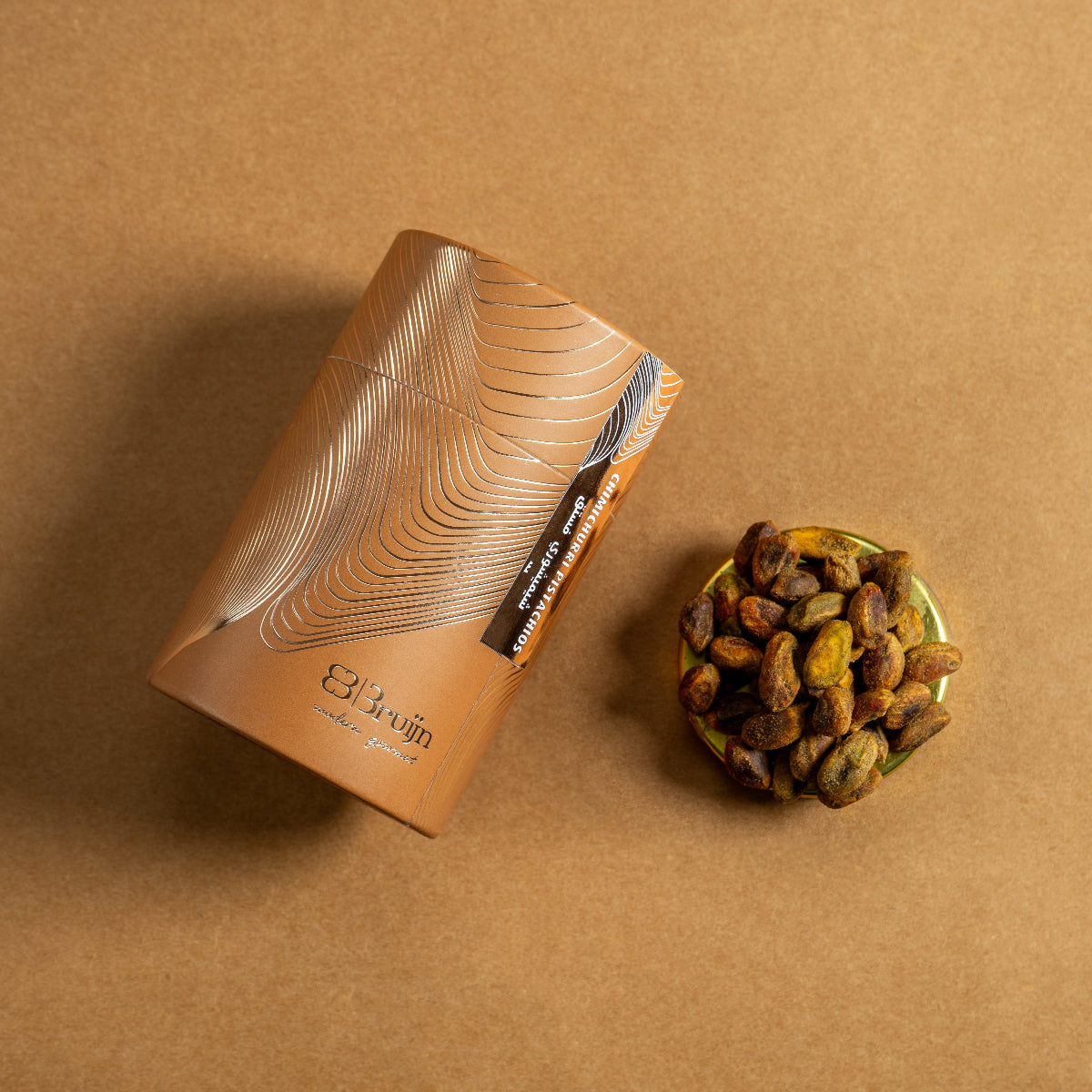 Brown cylindrical container of Bruijn Chimichurri Pistachios with minimalist design, containing pistachios coated in herb-rich chimichurri seasoning.