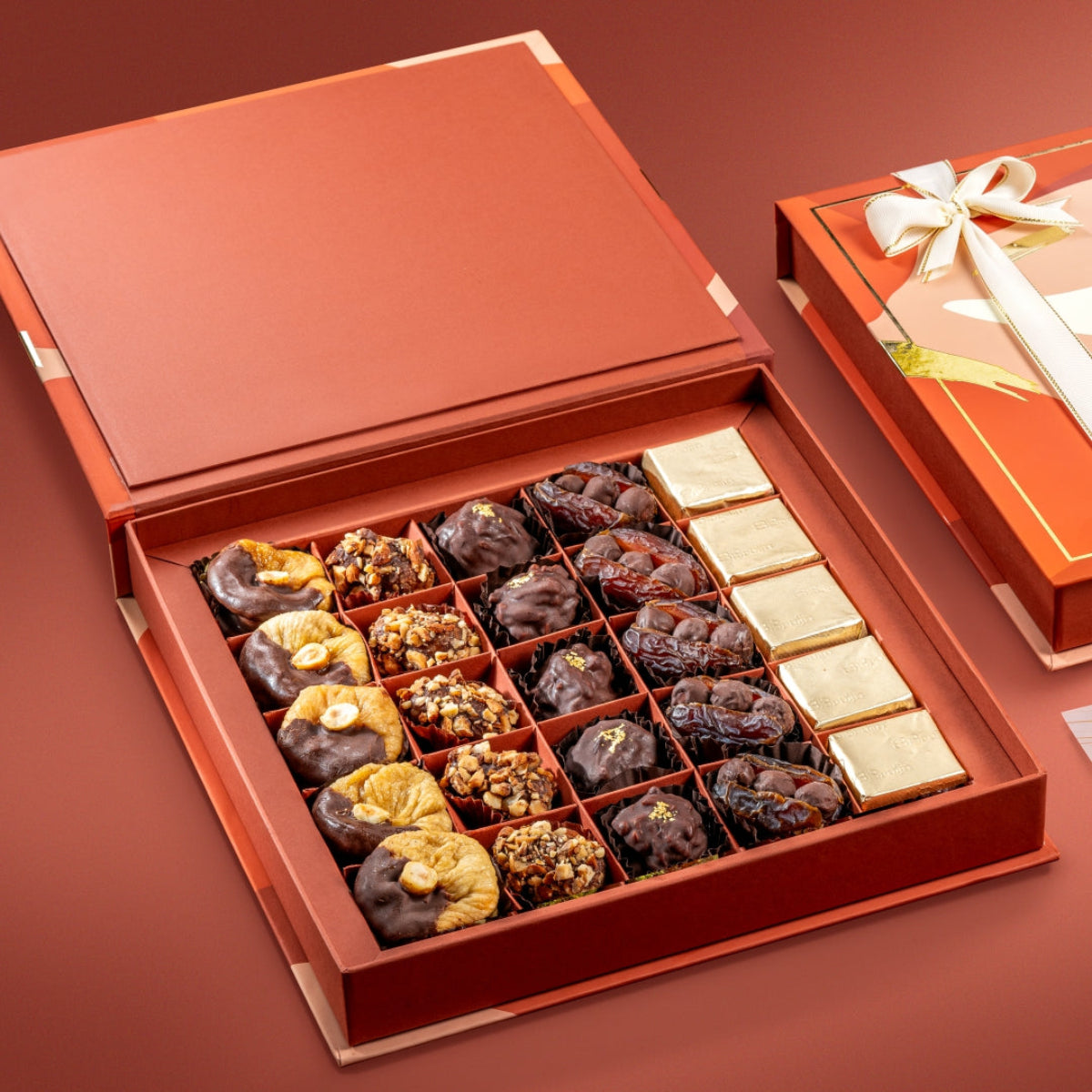 Open box of Bruijn Opulent Chocolate Collection showing figs, date truffles, almond rocks, stuffed dates, and dark chocolate.