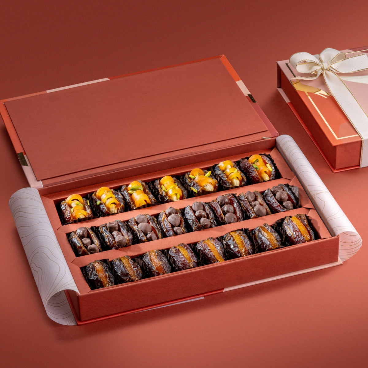 Open box of Regal Dates Collection with mejdool dates stuffed with cashews, mango peel, chocolate hazelnuts, and candied orange peel.
