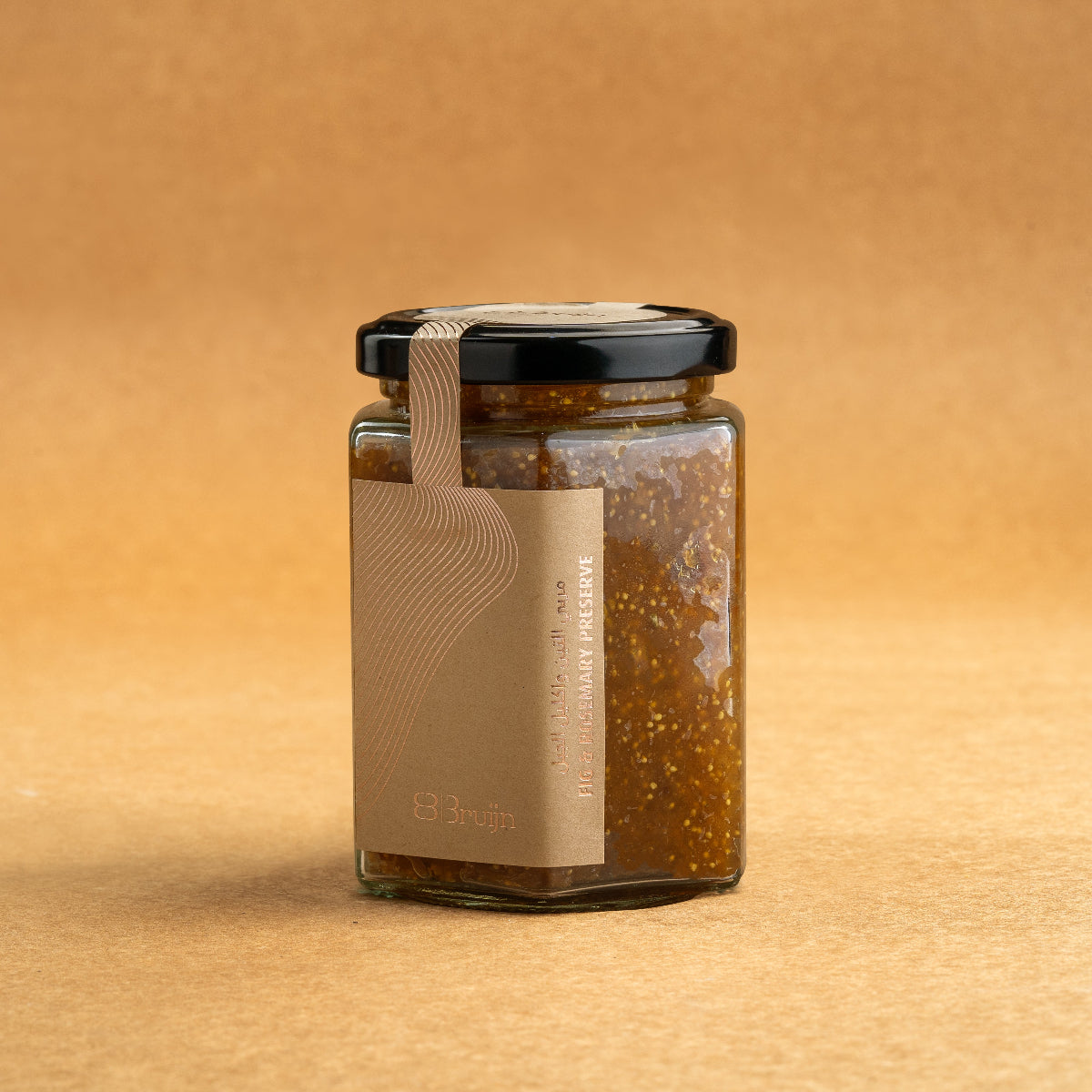 Glass jar of Bruijn Fig & Rosemary Preserve with black lid and kraft label, filled with grainy fig preserve infused with rosemary and orange zest.