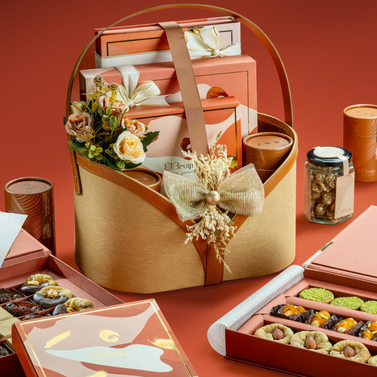 Medley Basket with regal box of dates, figs, and ranginak, candid chocolate box, petite paan bites box, nut jars, and cylinder of dried fruits and apple chips.