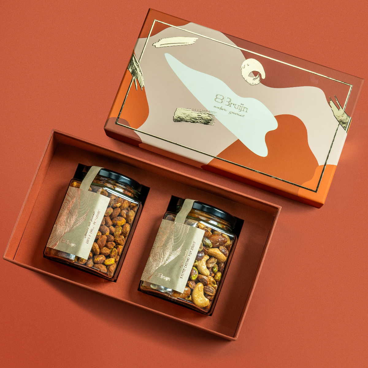 Modern Abundance Box with abstract patterned lid, containing two glass jars — one of Salted Caramel Nut Délice and one of Lime & Chilli Pistachios — nestled in a luxury gift tray.