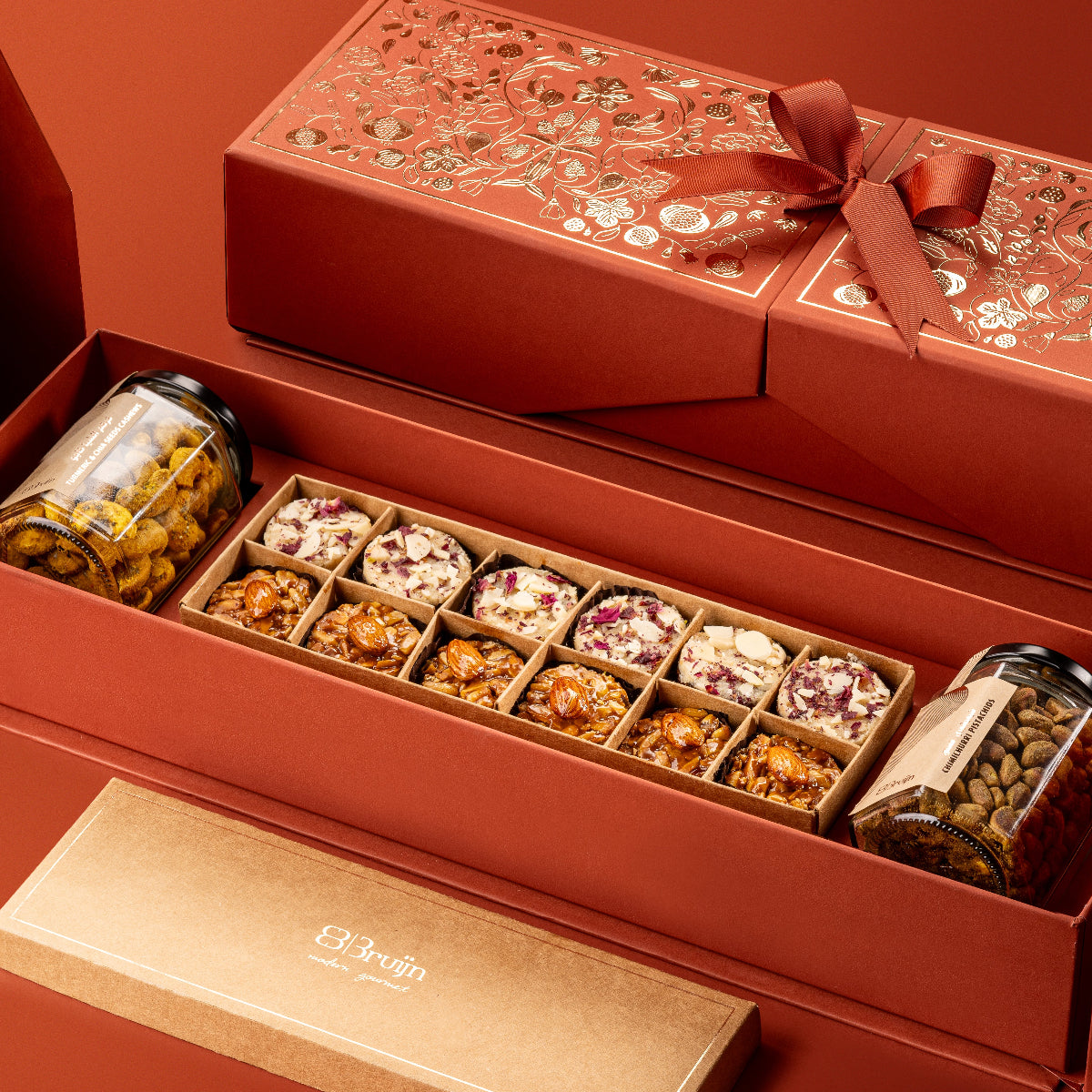 Royal Box from Stories of Bruijn Edition featuring jars of turmeric & chia cashews, chimichurri pistachios, and a craft box with Persian rose delights and fig & nut bites, elegantly packed in a red gift box with golden detailing.