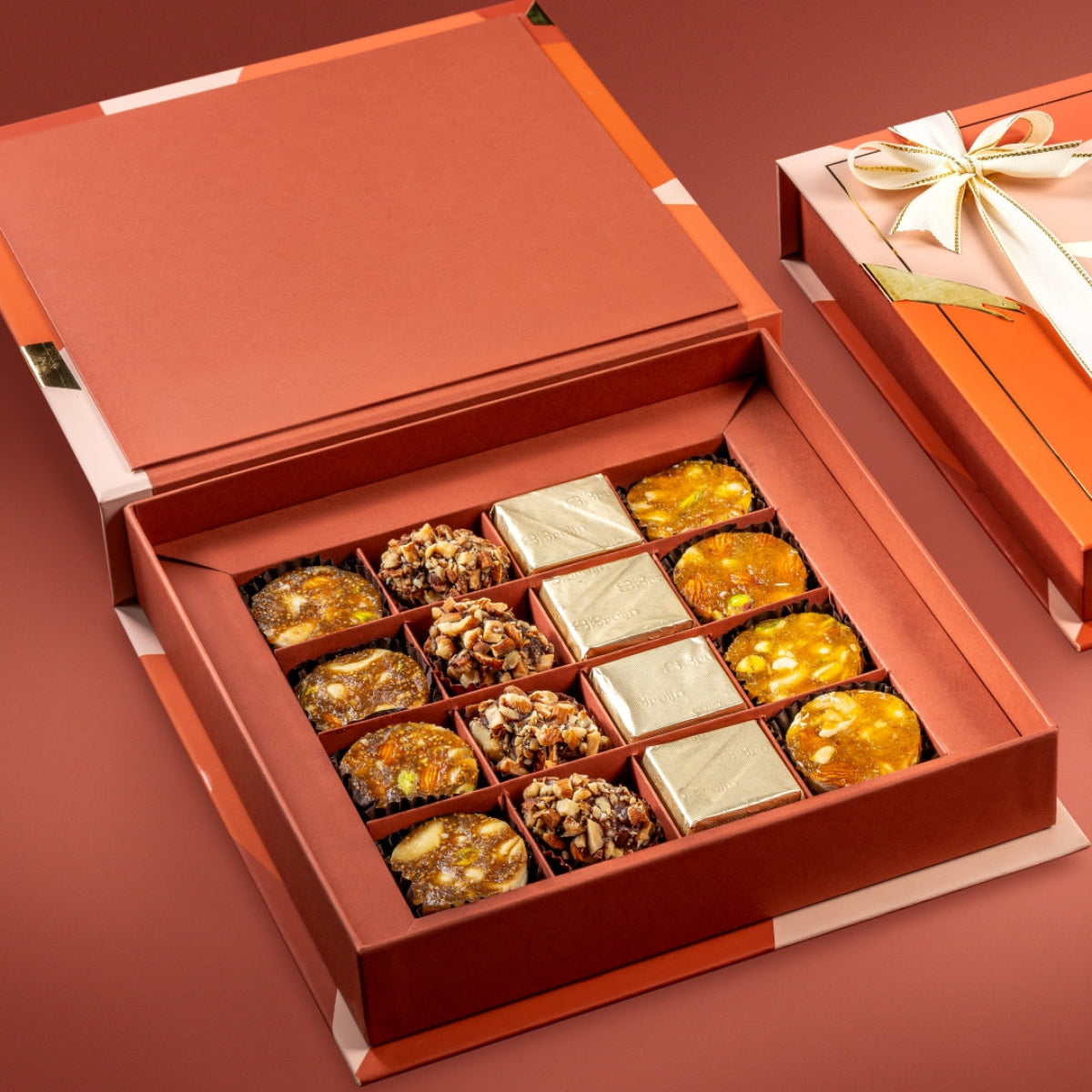 Open Motley Box showing assorted fig bites, date truffles, dark chocolate with nuts, and apricot bites arranged neatly in a festive gift box.