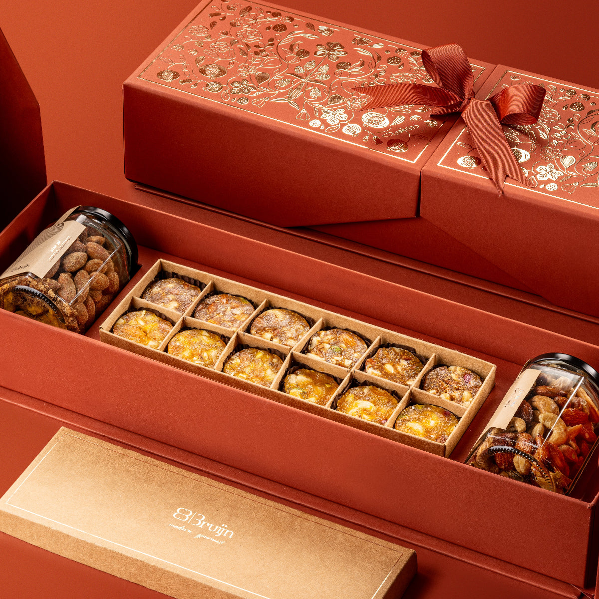 Royal Box from Stories of Bruijn Edition with smoked almonds, salted caramel nut délice, and fig, apricot & nut bites elegantly packed in a red gift box with golden floral detailing.