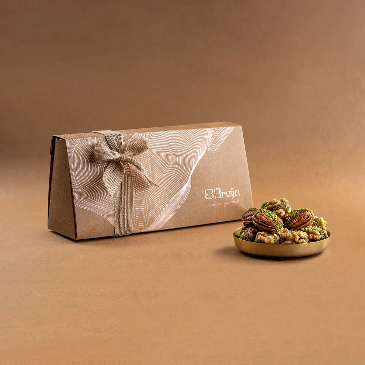 Elegant beige craft gift box tied with a bow, containing pecans & walnuts stuffed with dates and pistachio.