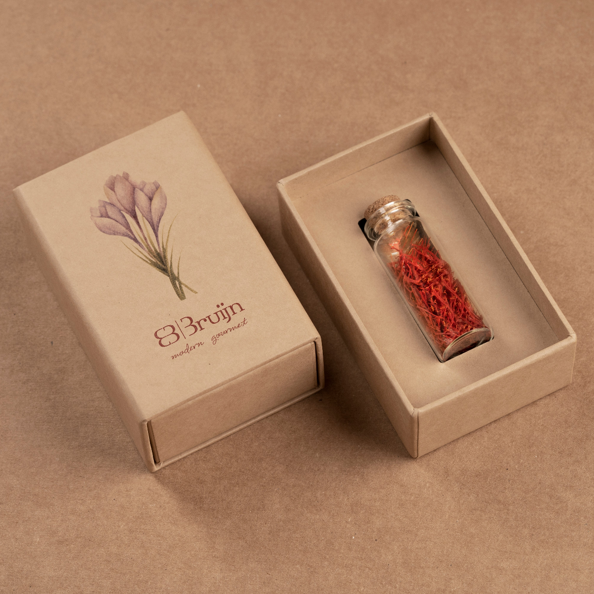 Elegant beige gift box with a vial of hand-harvested saffron strands, finest grade. Glass vial of premium saffron strands displayed in a minimal beige gift box.