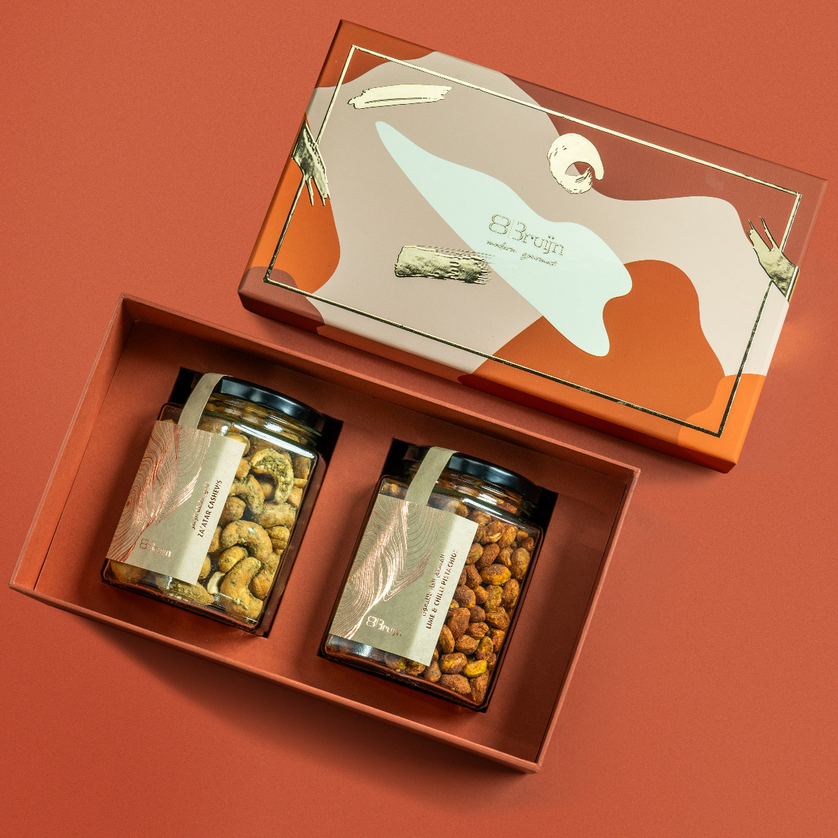 Modern Abundance Box with abstract patterned lid, containing two glass jars — one of Za’atar Cashews and one of Lime & Chilli Pistachios — in a premium tray.