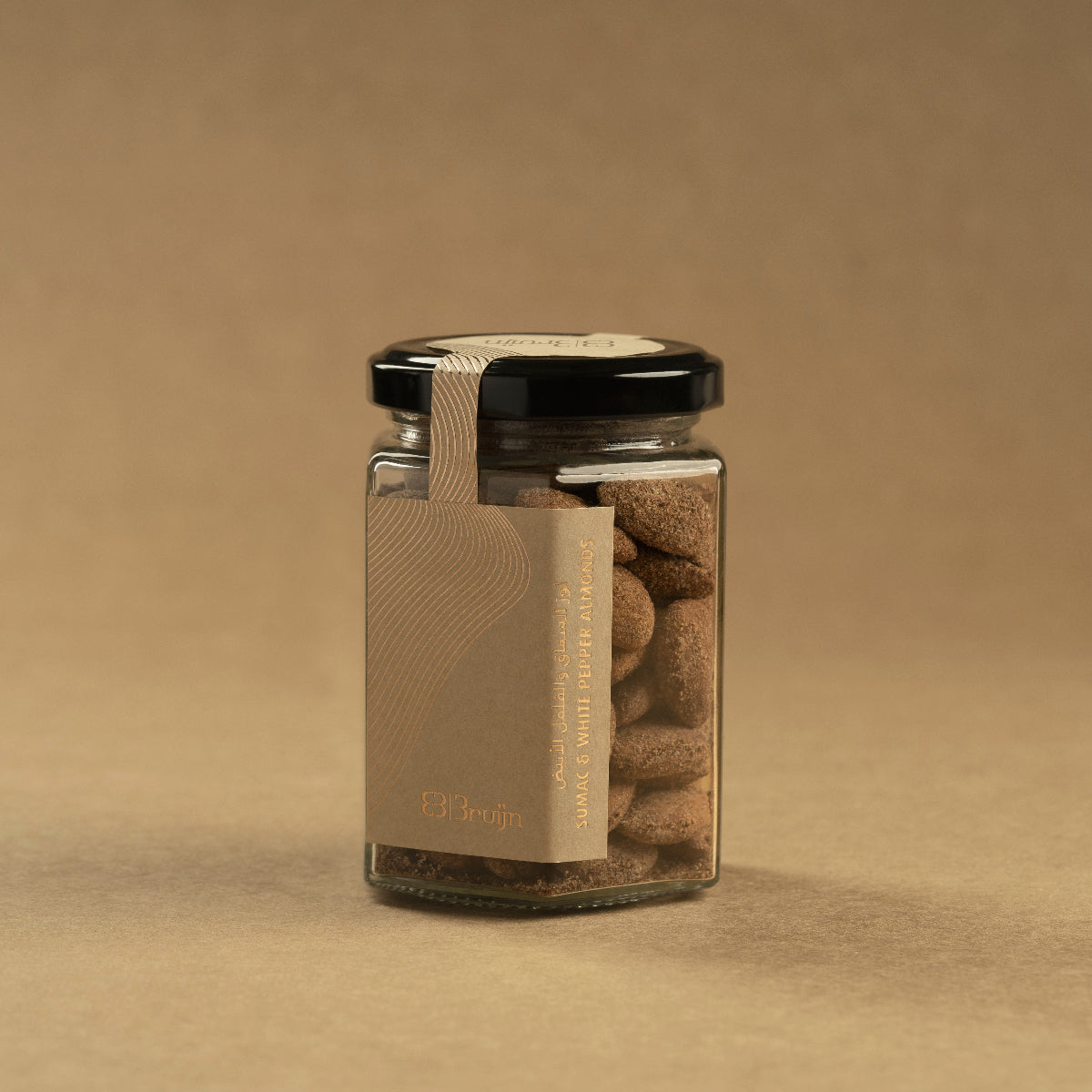 Glass jar of Bruijn Sumac & White Pepper Almonds with black lid and kraft label, filled with roasted almonds coated in a citrusy sumac and pepper seasoning.