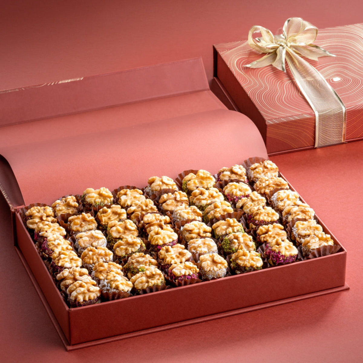 Elegant rust-colored walnut box tied with a golden ribbon, filled with assorted stuffed walnuts.