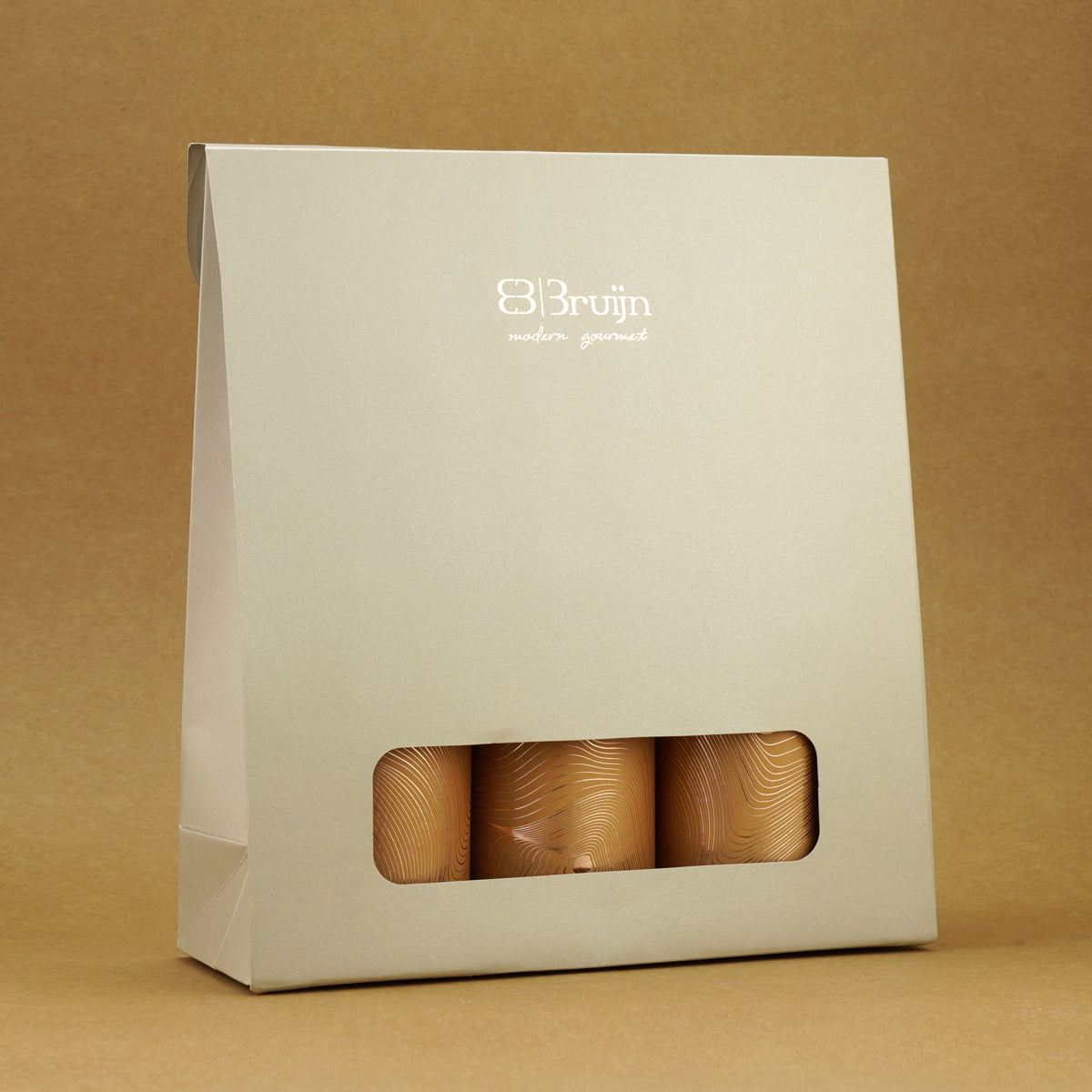 Sustainable gift bag with biodegradable cylinders holding apple chips, black truffle peanuts, and salted caramel nut mix.