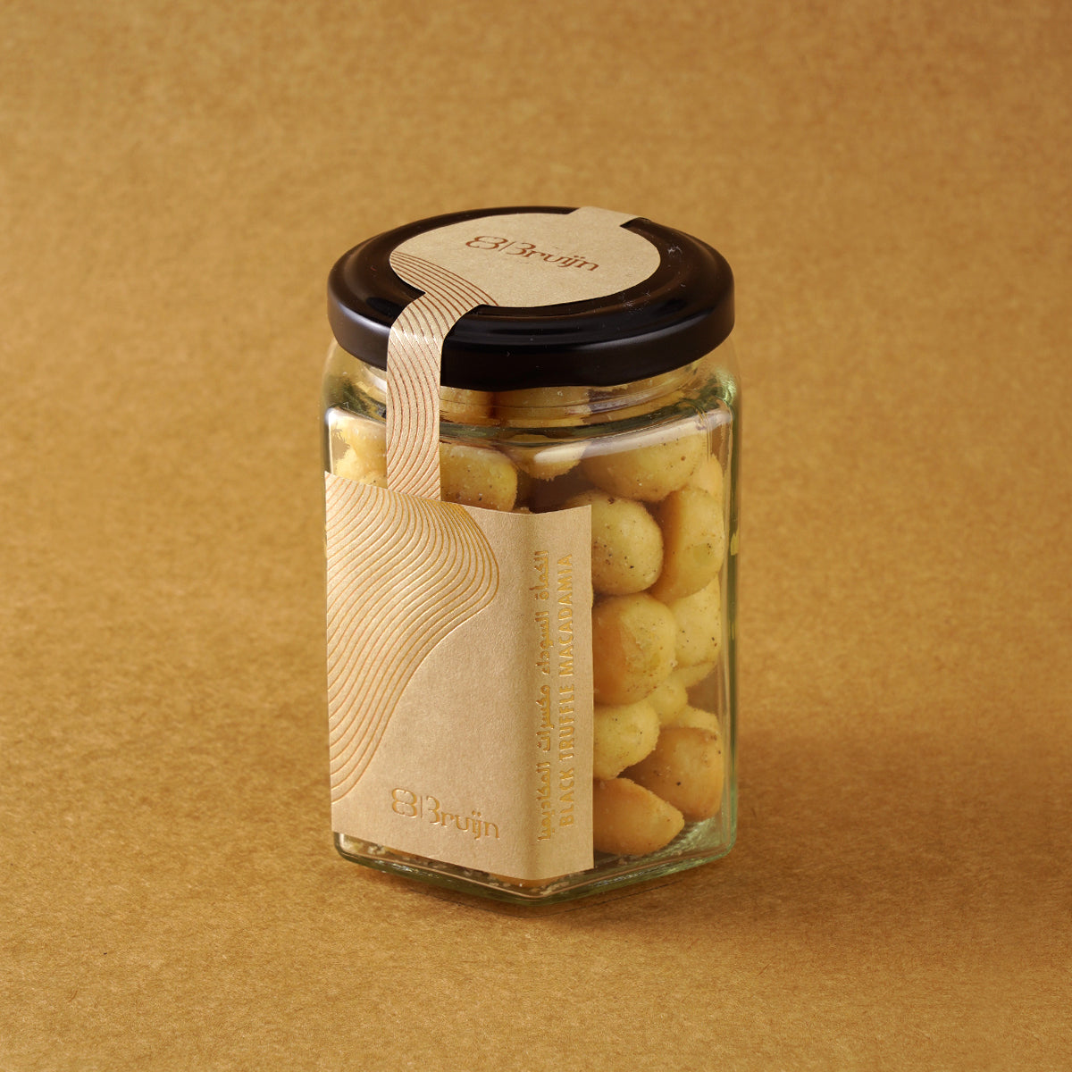 Glass jar of Bruijn Italian Black Truffle Macadamias with black lid and kraft label, filled with golden macadamia nuts coated in aromatic truffle seasoning.