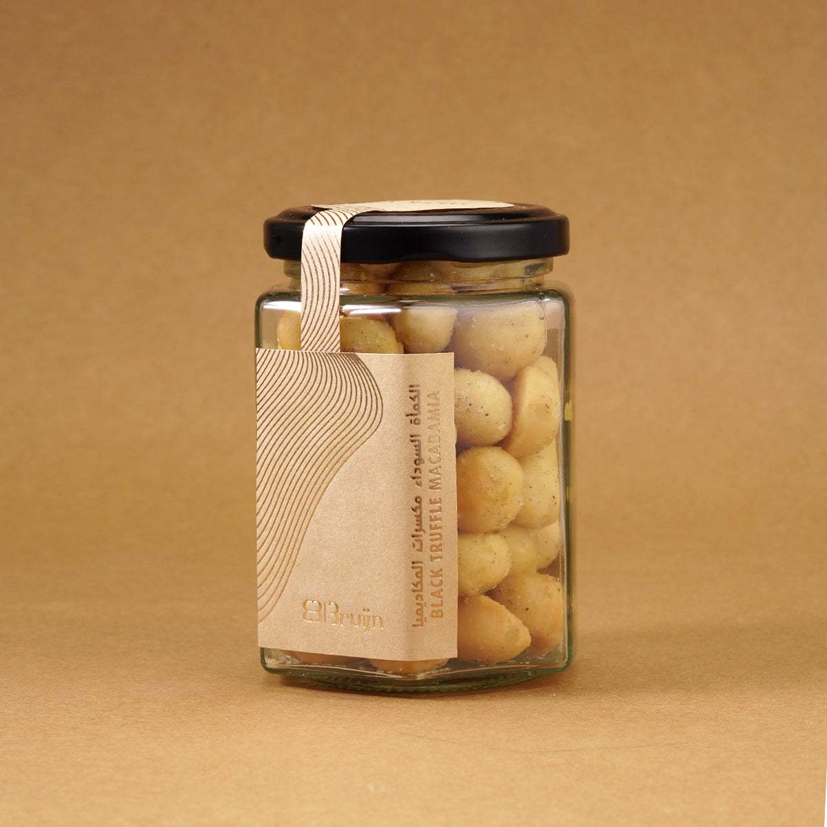 Glass jar of Bruijn Italian Black Truffle Macadamias with black lid and kraft label, filled with golden macadamia nuts coated in aromatic truffle seasoning.