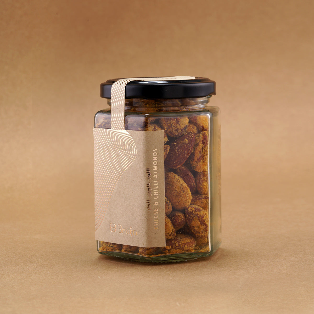 Glass jar of Bruijn Cheese & Chilli Almonds with a black lid and kraft label, showing golden almonds coated in cheese and chilli seasoning.