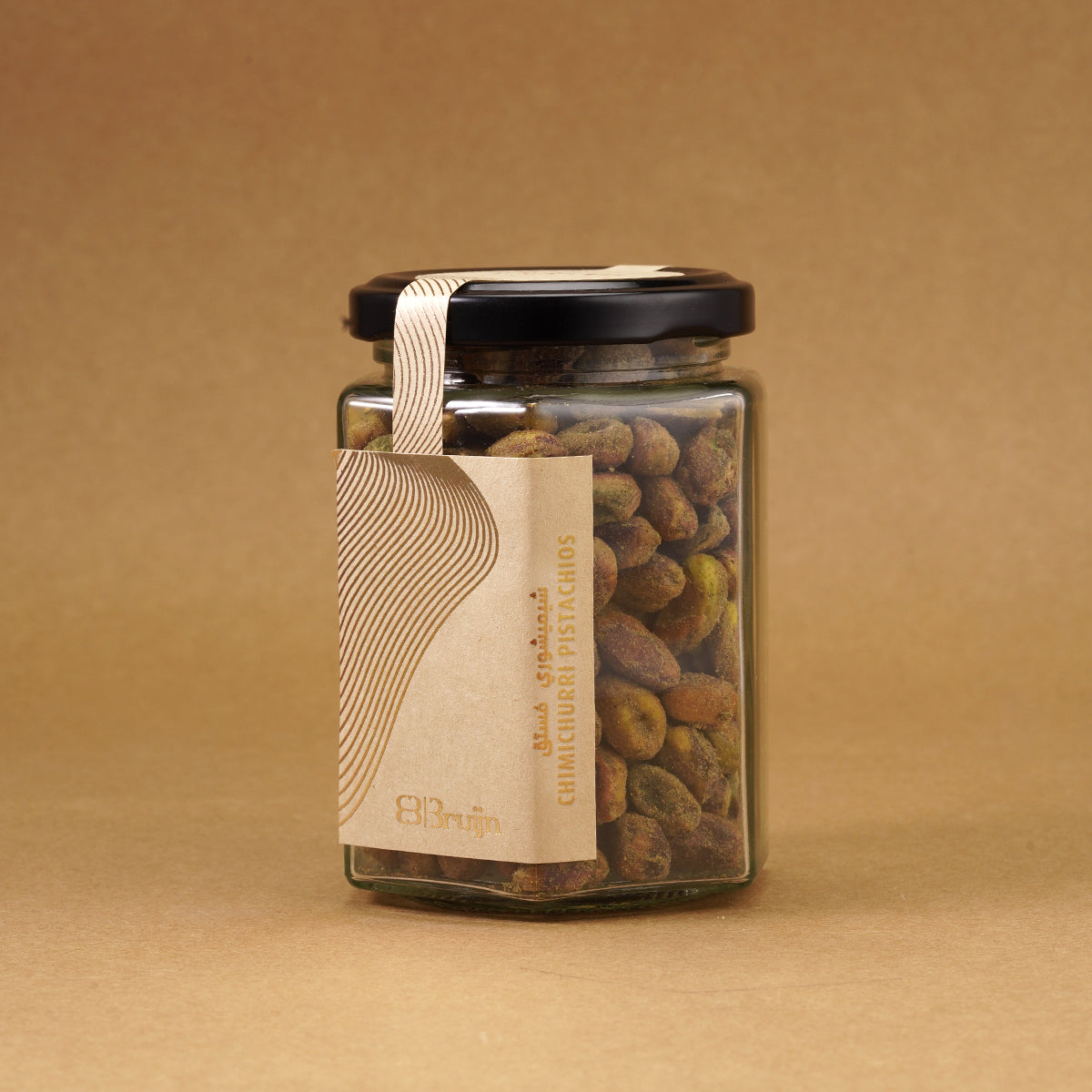 Glass jar of Bruijn Chimichurri Pistachios with black lid and kraft label, filled with pistachios coated in green herb and spice chimichurri seasoning.