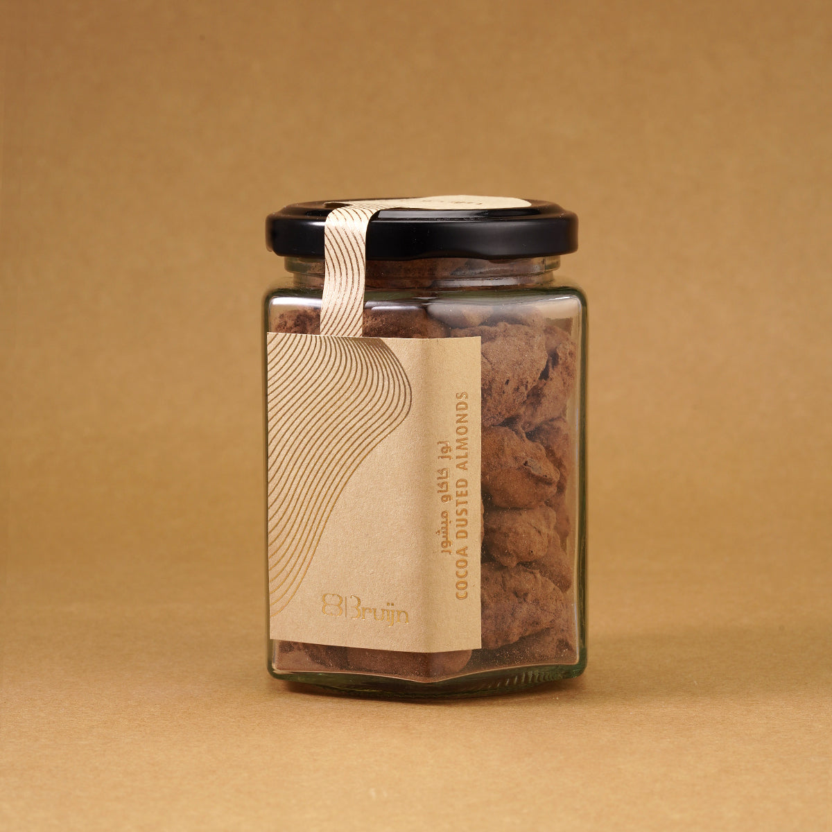 Glass jar of Bruijn Cocoa Dusted Almonds with black lid and kraft label, filled with chocolate-coated almonds dusted in rich cocoa powder.