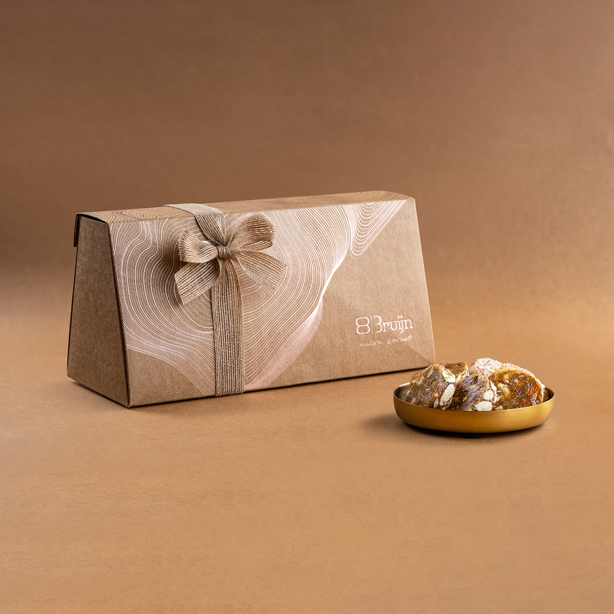 Craft Box with 1kg fig & nut bites, roasted nuts rolled in grainy fig paste, placed alongside a golden plate of bites.