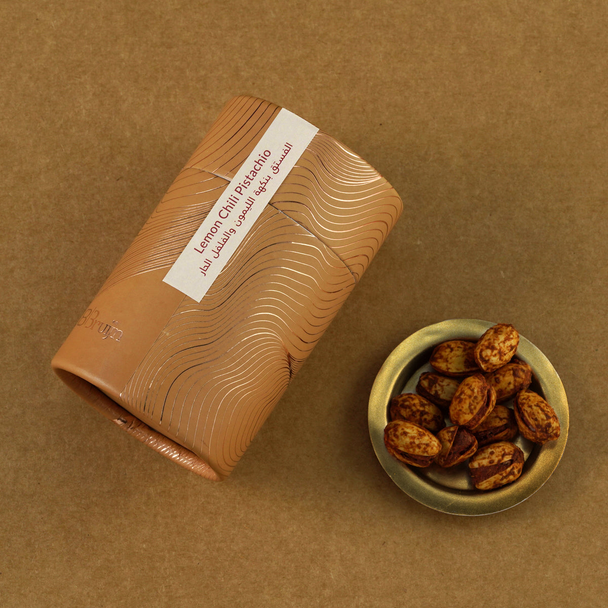 Brown cylindrical container of Bruijn Persian Lime & Chilli Pistachios with minimalist design, containing pistachios coated in tangy lime and spicy chilli seasoning.