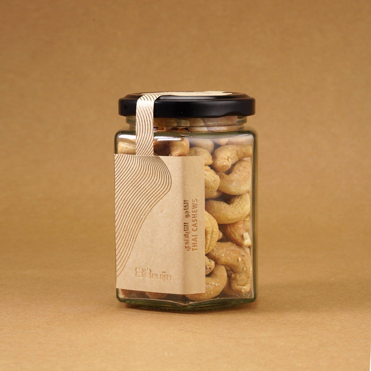 Glass jar of Bruijn Thai Herb Cashews with black lid and kraft label, filled with golden cashews coated in aromatic Thai herbs and spice seasoning.