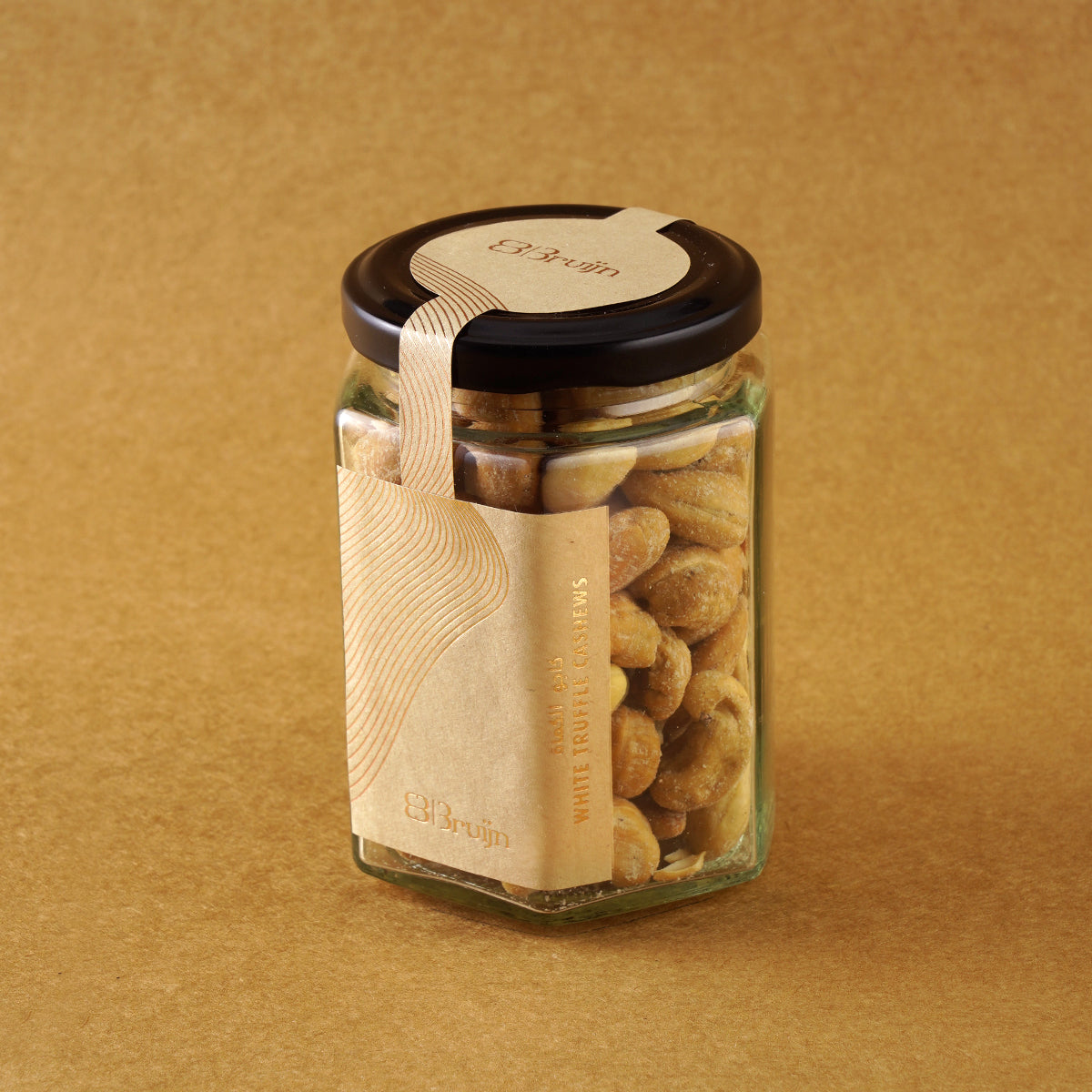 Glass jar of Bruijn Italian White Truffle Cashews with black lid and kraft label, filled with golden cashews coated in aromatic white truffle seasoning.