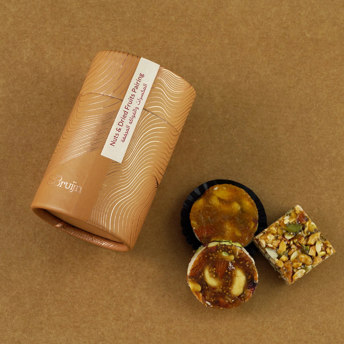 Cylinder pack of fig and apricot nut bites with roasted nuts, presented in eco-friendly packaging, ideal for festive gifting.