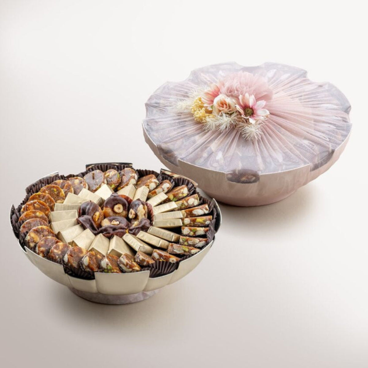 Fluted Silver bowl with Rose Quartz filled with artisanal fig and nut bites alongside pure cacao dark chocolate with nuts, beautifully arranged for gifting.