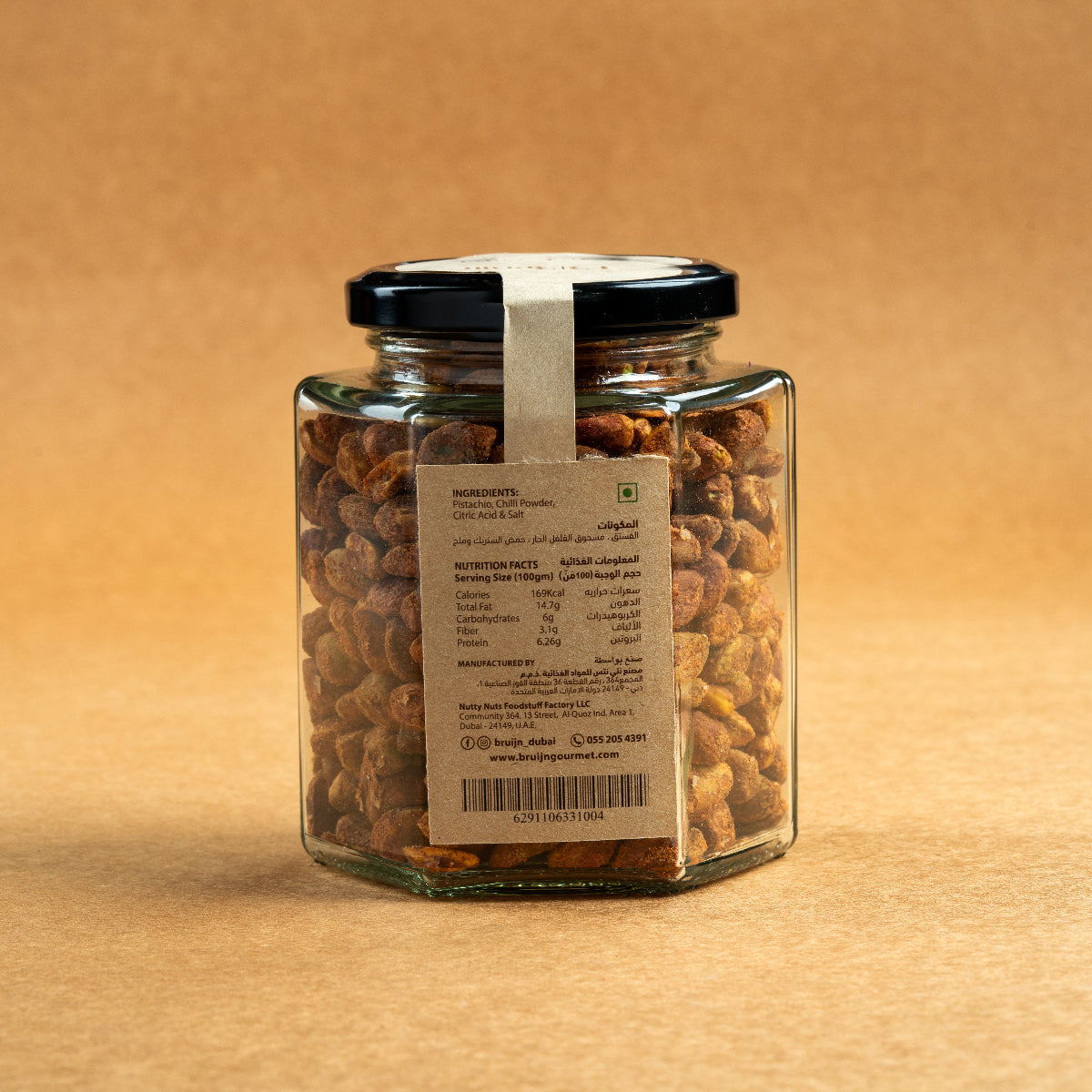 Glass jar of Bruijn Persian Lime & Chilli Pistachios with black lid and kraft label, filled with spiced pistachios coated in lime and chilli seasoning.