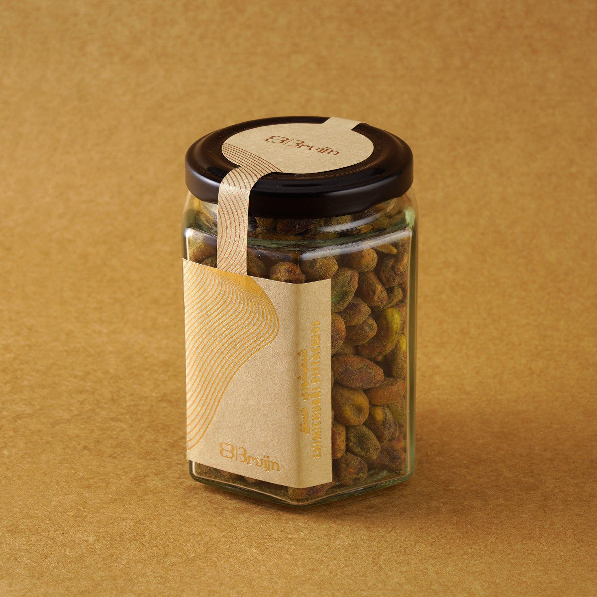 Glass jar of Bruijn Chimichurri Pistachios with black lid and kraft label, filled with pistachios coated in green herb and spice chimichurri seasoning.