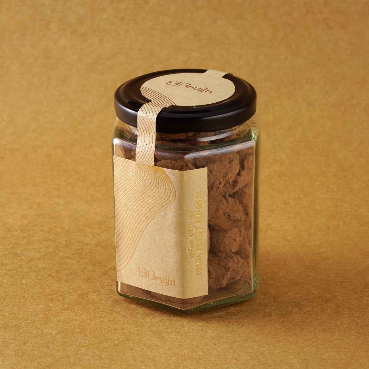 Glass jar of Bruijn Cocoa Dusted Almonds with black lid and kraft label, filled with chocolate-coated almonds dusted in rich cocoa powder.