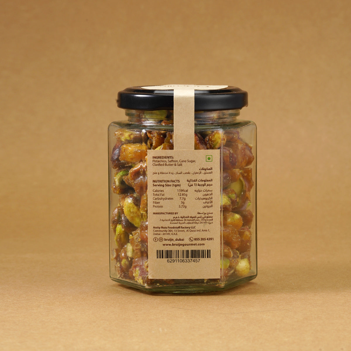 Glass jar of Bruijn Saffron Caramel Pistachios with black lid and kraft label, filled with golden caramel-coated pistachio kernels infused with saffron strands.